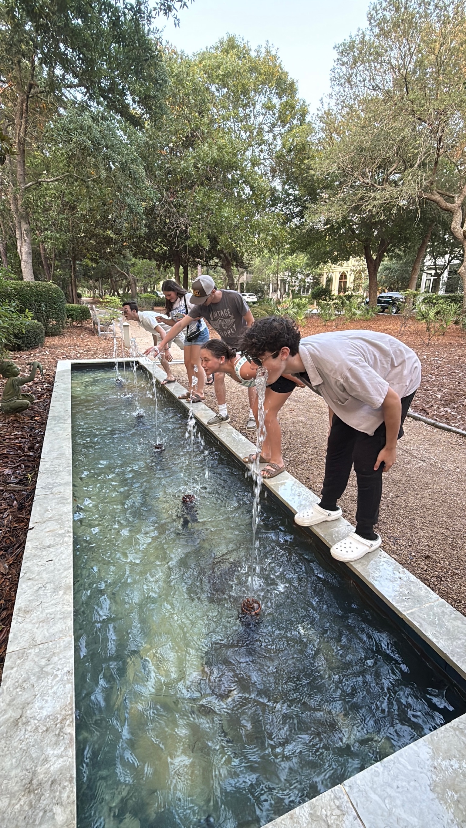Photo of the LoBuglio and family friend's children leaning over a fountain, pretending to drink from it.