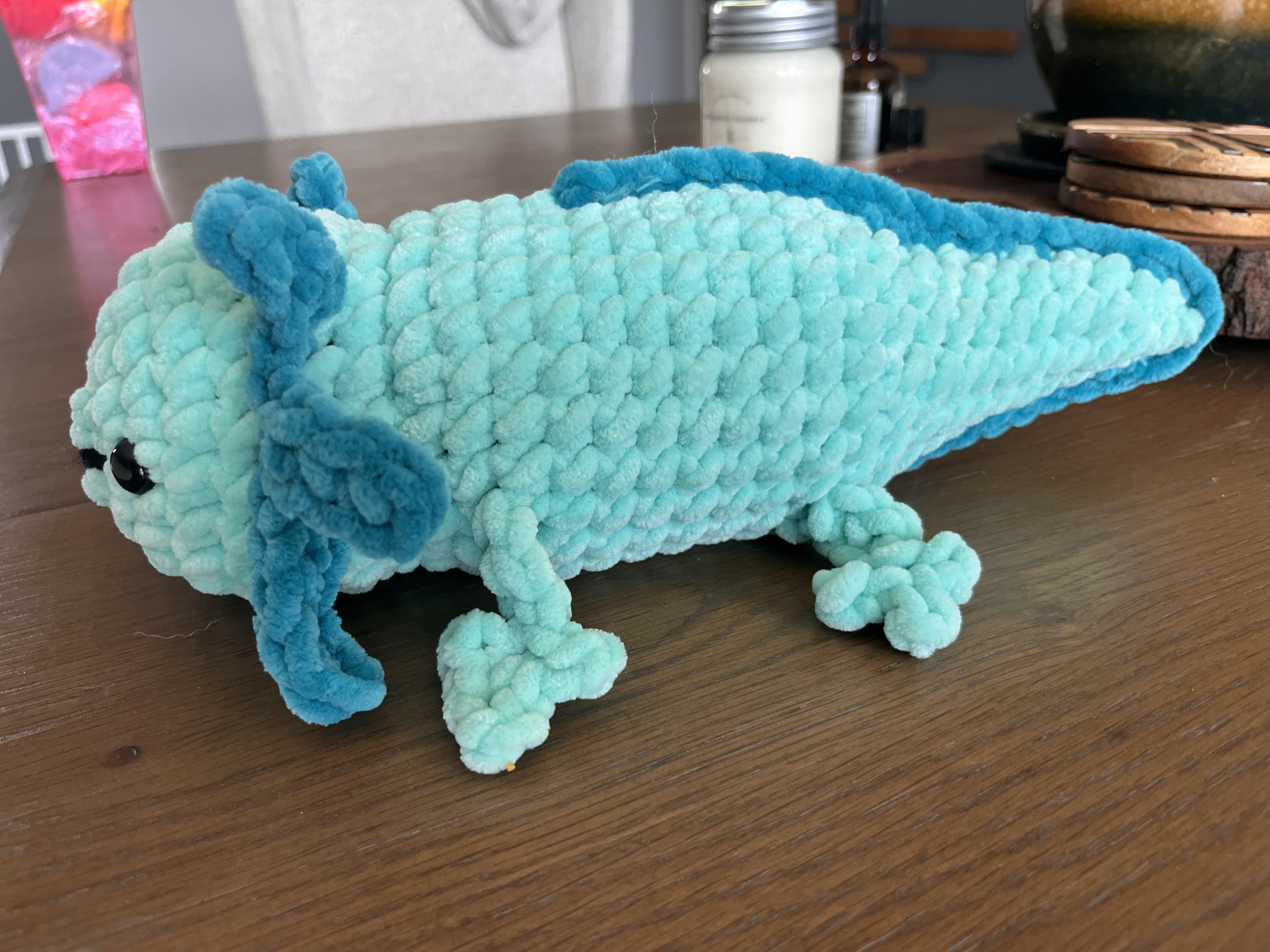 Left facing photo of a blue crocheted axolotl