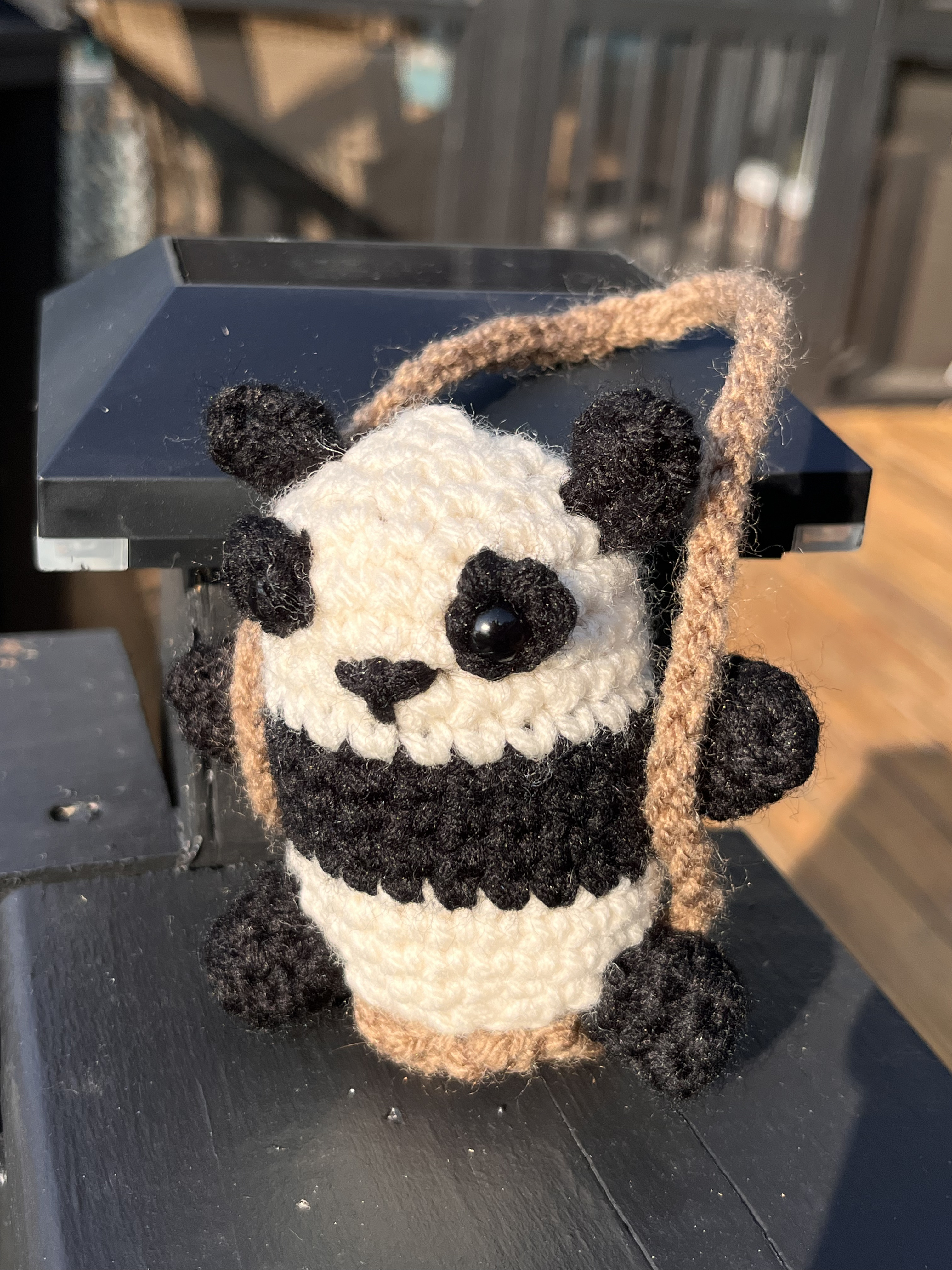 Photo of a crocheted panda on a swing.